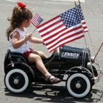 Little Girl on Toy Car with American Flags